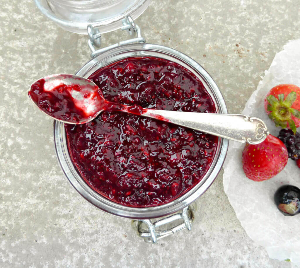 overhead shot of a jar of berry jam with a small spoon on top