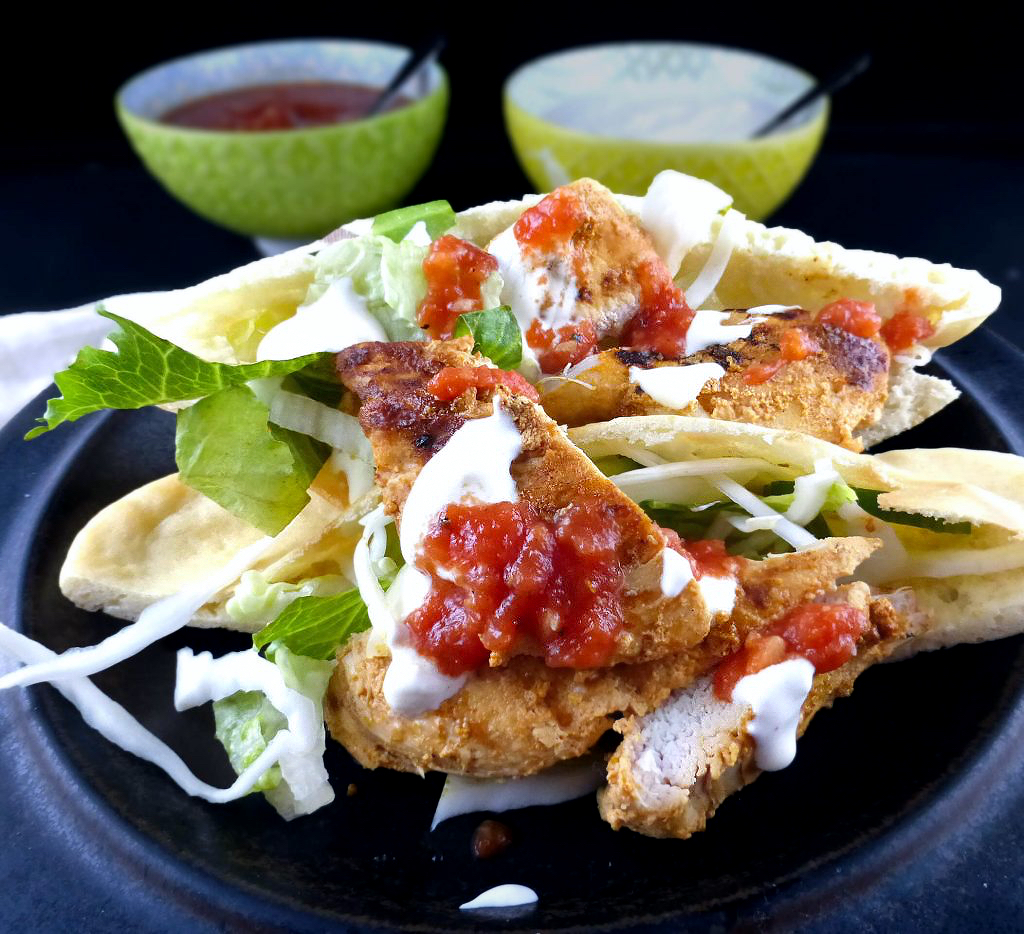 image of chicken kebab with lettuce and sauces with two bowls behind in a dark background