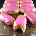 pink iced finger buns on a wooden board