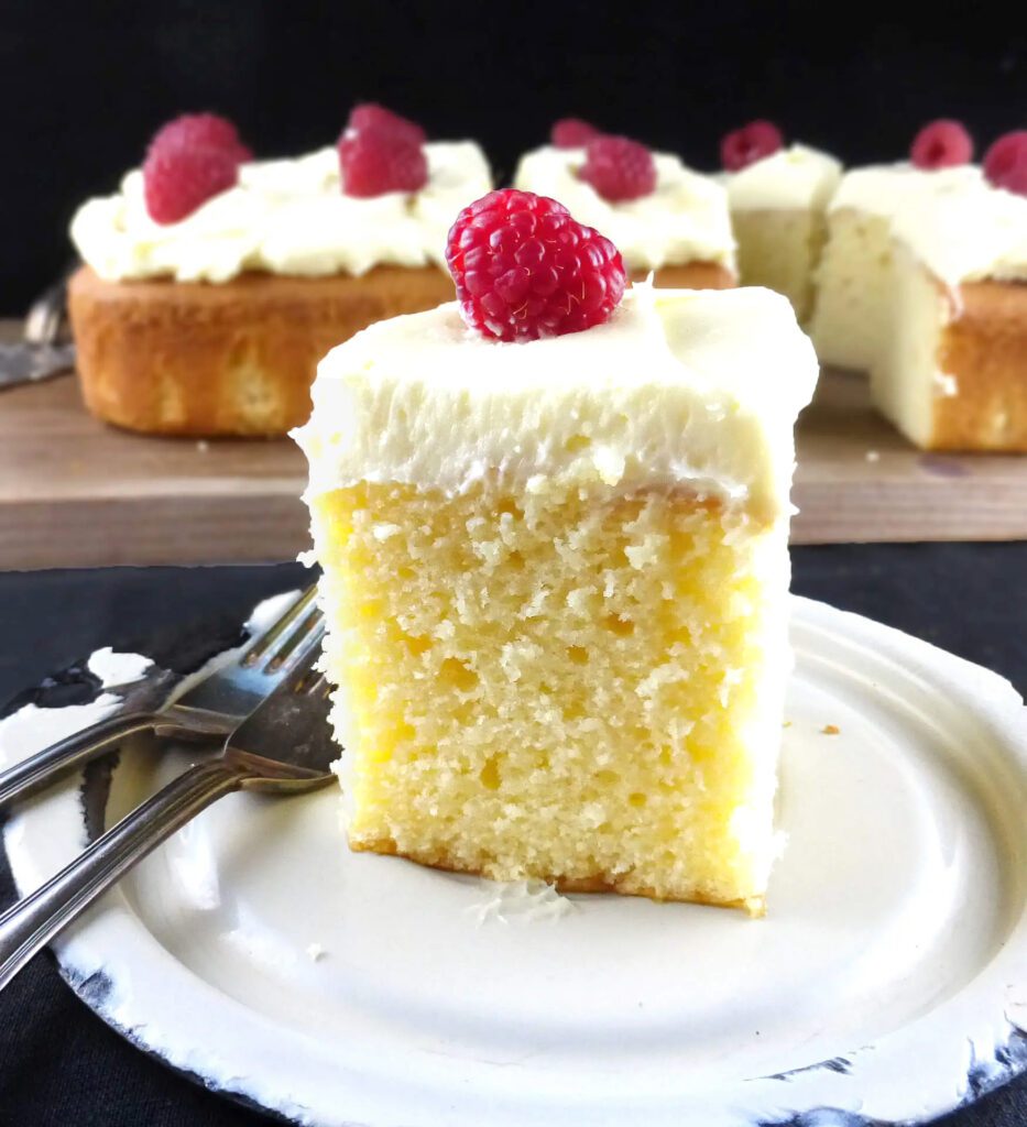 slice of white chocolate cake with frosting and a raspberry on top