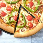 Overhead view of a spelt crust pizza with a cut slice