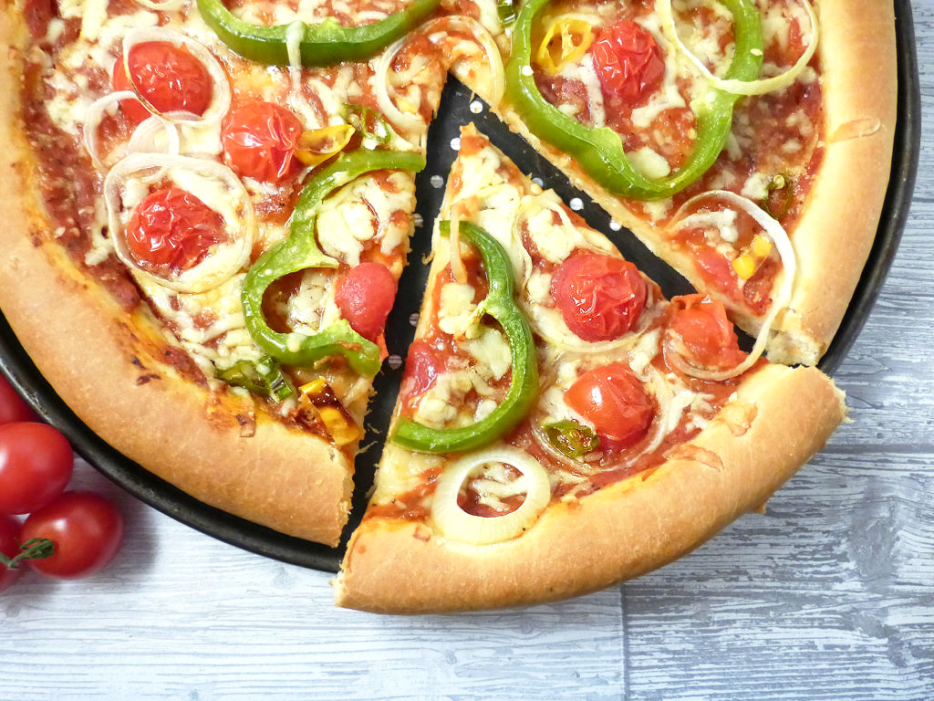 overhead view of a vegetable pizza with a slice cut out