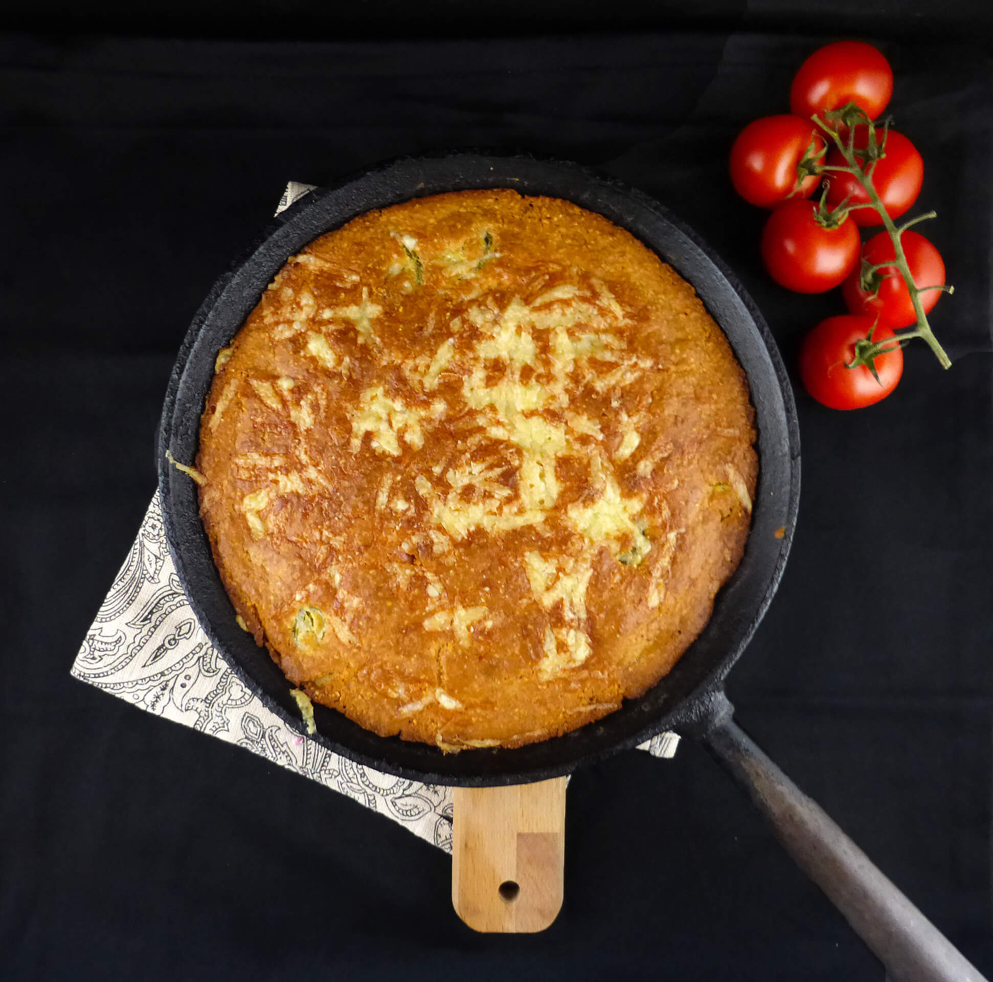 overhead shot of cornbread in a skillet on a dark surface and background